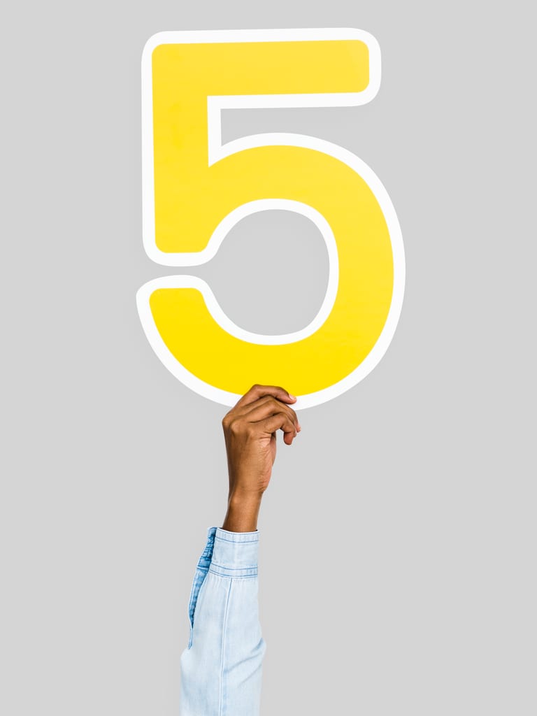 escape-room-team-building-houston-5-questions Hand holding up a large yellow number five against a grey background, representing the five questions to ask before booking an escape room team building in Houston